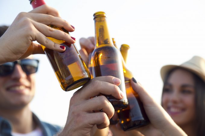 Outdoor portrait of group of friends toasting with bottles of beer.