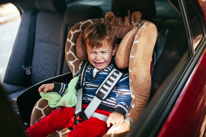 Crying baby boy in car seat.