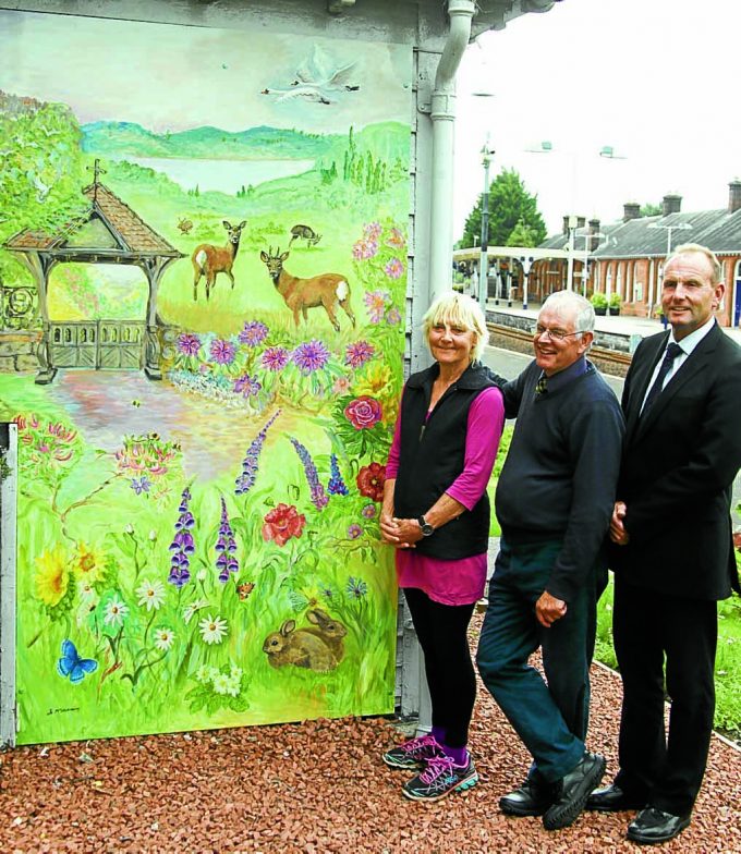 MURAL . . . artist Jo McSkimming with Mark Jardine from the People's Project and Louis Wall from the South West Railway Adopters Gardening Group at a mural created for a wall at Dumfries Railway Station